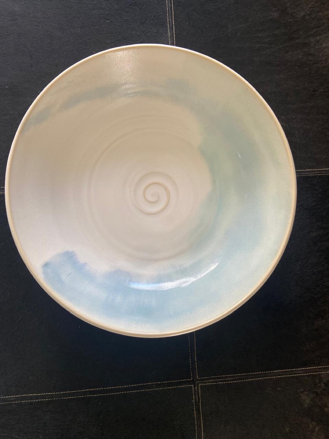 Tigela clara com esmalte azul em aquarela e a espiral do torno no centro
