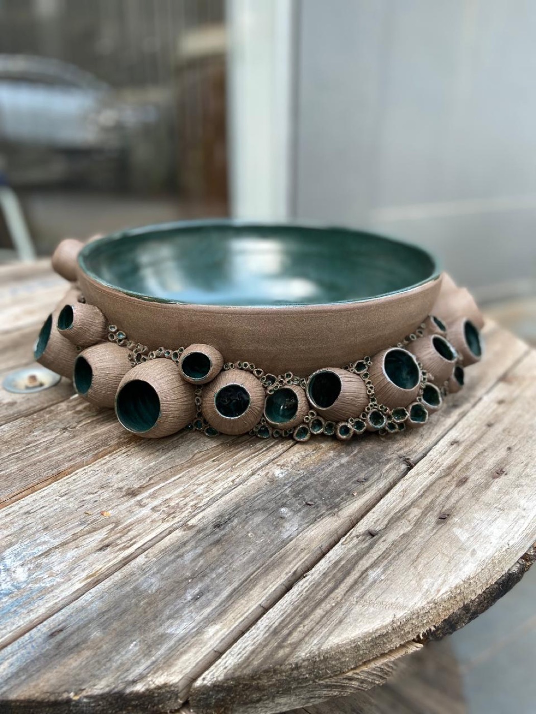 Tigela de esmalte verde-escuro com uma coroa de cracas em barro aparente