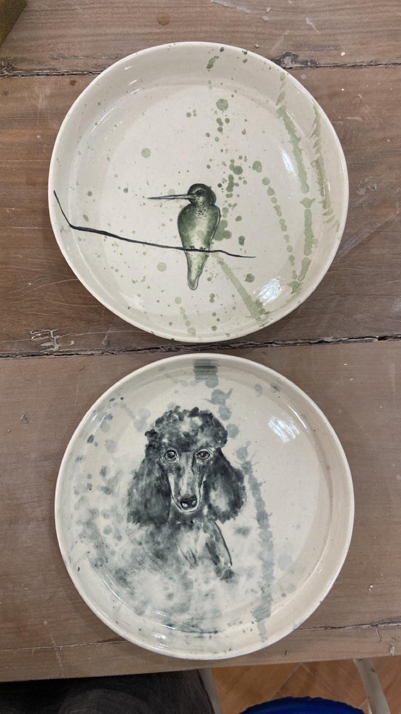 Dois pratos pintados: um pássaro e o retrato de um cachorro