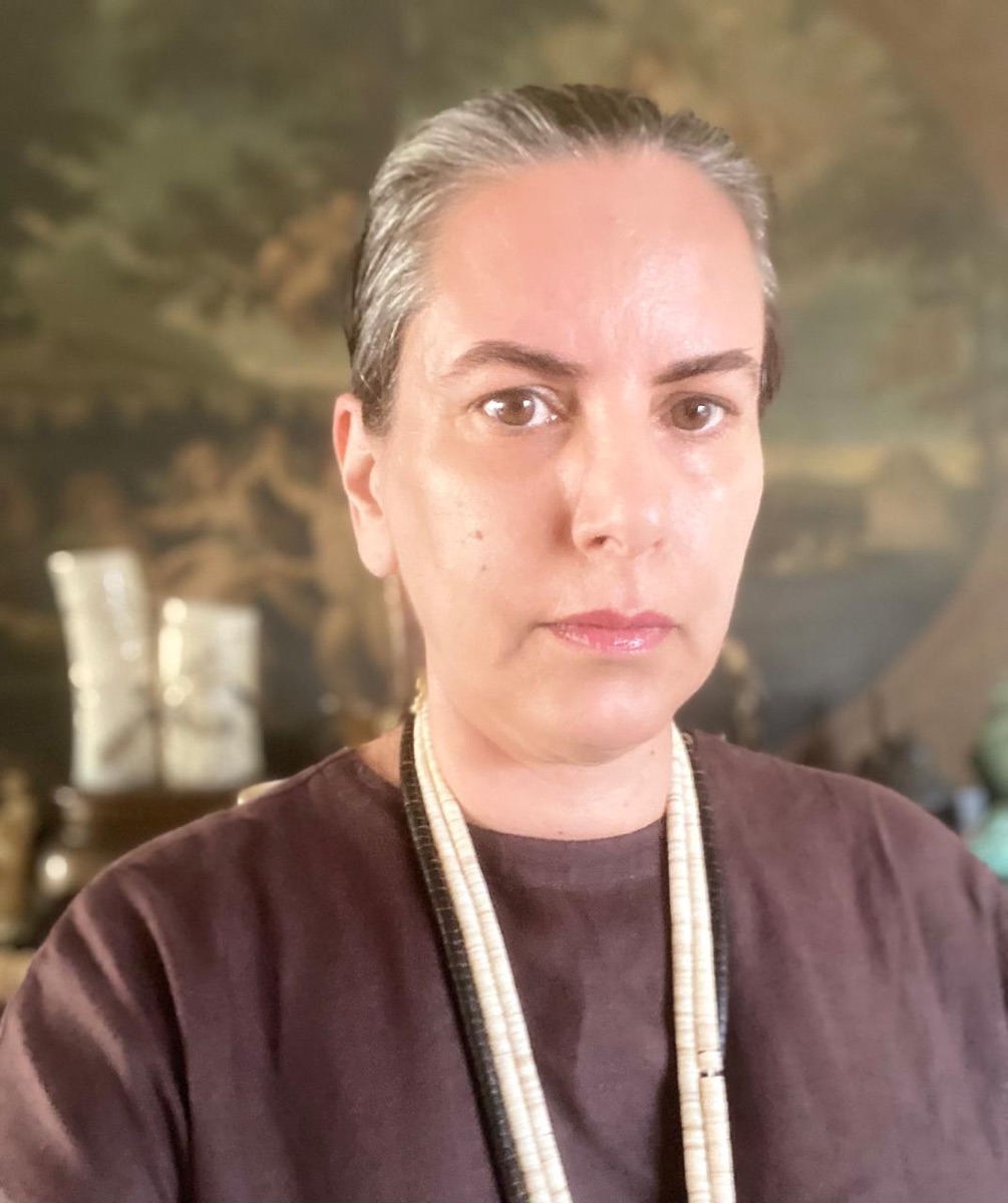 Retrato de Roberta Lyra, de camiseta escura e colares de contas